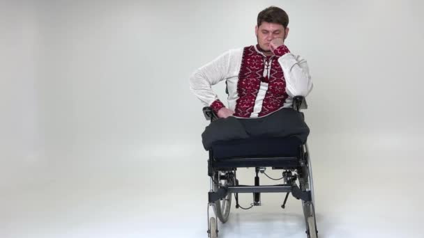一个英俊的残疾士兵坐在轮椅上与残疾作斗争的老兵身上 年轻的男性看着镜头 神情忧郁 很不高兴 他穿着军服坐在主席职位上 — 图库视频影像