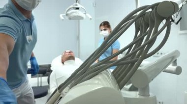 Mavi eldivenli doktor, hastaların dişlerine, temizlenmesi gereken plağın nerede olduğunu gösteren bir merhem sürüyor. Dişçi Ukrayna Vinnitsa 26.12.2022 kliniğinde diş temizliği ve cilalama yaptırıyor.