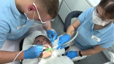 Mavi eldivenli doktor, hastaların dişlerine, temizlenmesi gereken plağın nerede olduğunu gösteren bir merhem sürüyor. Dişçi Ukrayna Vinnitsa 26.12.2022 kliniğinde diş temizliği ve cilalama yaptırıyor.