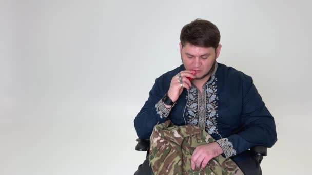 大人ハンサムな男35歳制服を着た軍人が座って喫煙彼はウクライナの彼の指の紋章にリングを持っていますウクライナの旗は保護ジャケットに縫い付けられていますウクライナの歴史 — ストック動画