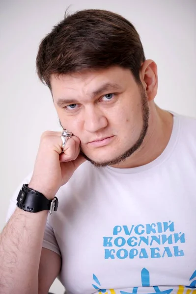 strength and courage piercing eyes handsome adult man with blue eyes leaned on his arm and looks into the frame. He thought on his white T-shirt, it says Russian ship. Get out of here.