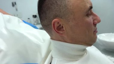 Diş hekimliği yapan bir adamın kafasının altına beyaz bir yastık yerleştirilir. Kafasının ve boynunun şeklini alır. Bisküviler diş sağlığı kliniğinde diş protezleri takar.. 