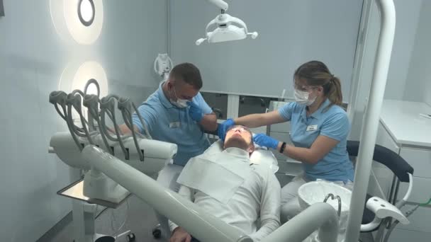 在牙科诊所内 为治疗牙齿治疗 填补口腔内蛀牙 防止蛀牙 口腔医学的概念 男子和年轻男性牙科诊所 — 图库视频影像