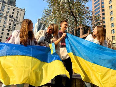 Ukrayna 'da dört Ukraynalı nakışlı gömlek giymiş insan Ukrayna' da barışın mutlu sonla bittiği iki Ukrayna bayrağıyla meydanda duruyor. Göçmen mültecilerin aileleri üç kadını bir araya getiriyor.