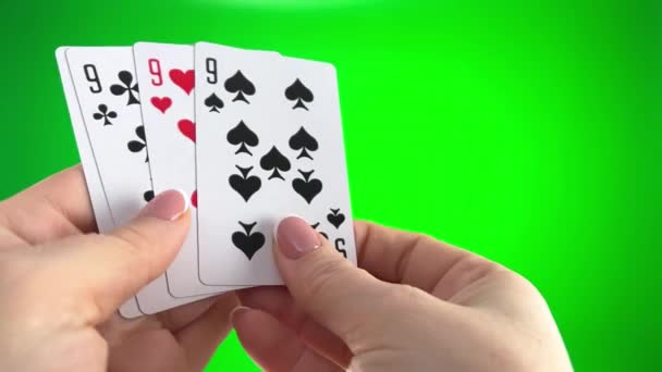 フランスのマニキュアで女性の手 女性はカードを並べ替え それらの折り目を調べ 同じスーツの左のファン4枚のカードのように広がります緑の背景に4つの9を保持手クローズアップ — ストック動画