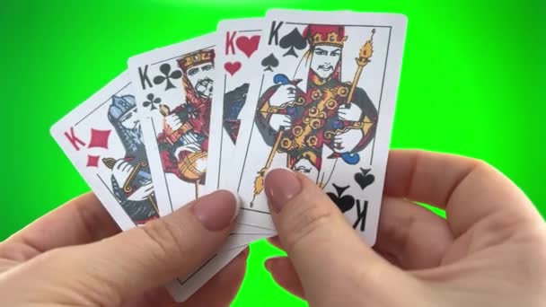 フランスのマニキュアで緑の背景クローズアップ女性の手に4つのキングカードを保持手 女性はカードを並べ替え折り目を調べ同じスートのファン4枚のカードのように広がり — ストック動画