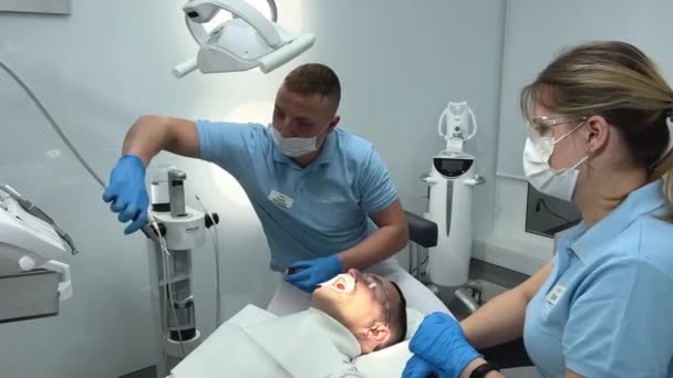 専門医歯科医試験保持ドリルツール患者が歯科スタジオで歯科医として働く幸せなヒスパニック男性の歯科センター嘘 人々の口腔衛生 病院での健康管理高品質4K — ストック動画