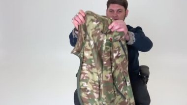 Tekerlekli sandalyedeki adam savaştan paltosunu çıkartıyor Ukrayna 'nın gömlekli amblemini incelerken onu düzeltiyor. Askeri üniforma kamuflajında.