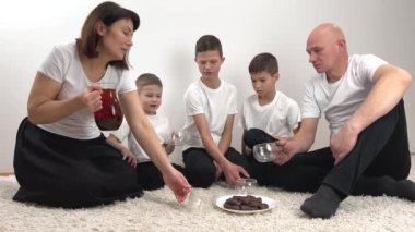 Birlik konsepti aile çay partileri, beyaz çay, siyah çikolata parçalı kurabiye, beyaz tişörtler, üç oğul, anne ve baba samimiyeti hafta sonu kahvaltısı.