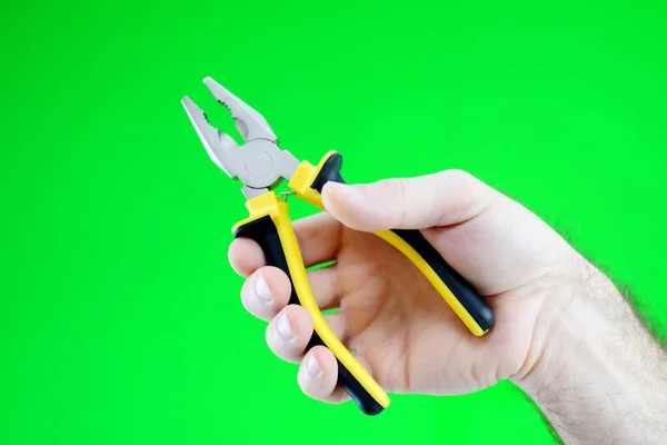 Cropped pliers with yellow orange handles Chroma key Green background Pliers in the hands of a man High quality photo Repairman call master