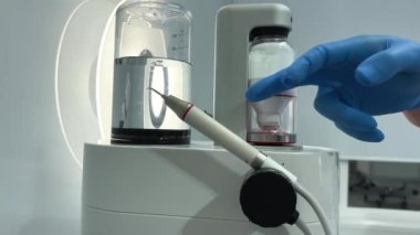 airflow device dantist lip and cheek dental retractor young doctor man takes a device for cleaning teeth and brings it to the Patient the patients mouth is open special crap open teeth nurse sits