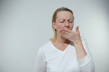  woman is tired she is bored yawns covering mouth white background housewife real person no hairstyle no makeup french manicure simple woman real people everyday life concept came home from work