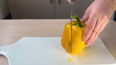 Knife cuts the red pepper. Slicing sweet pepper on wooden cutting board. Male hands cut with knife large red bell pepper. Closeup cut the sweet pepper. Healthy eating concept. Diet food.Slow motion
