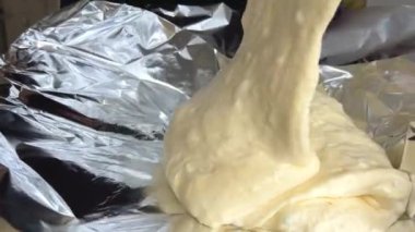 Pouring Dough Into Form Baking thick shiny stream of biscuit dough is poured onto the foil it lays down like a cream in layers for baking delicious homemade pastries lightness smoothness shiny