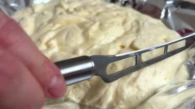 womans hand levels dough knife slides over shiny thick batter levels surface on foil homemade pastries expensive cakes biscuit dough eggs flour sugar knife holes skips dough it lays down in layers
