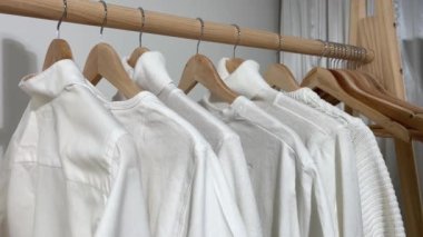 wooden hanger on it is lot of white mens clothing shirts and t-shirts sweaters womens hands start their choice looking for a gift for a man to celebrate going through things looking at the quality
