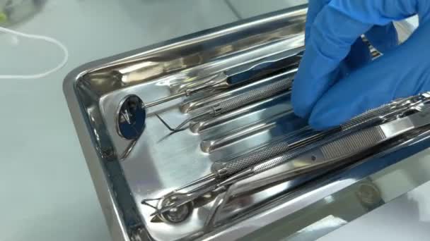 青い滅菌手袋の認識できない歯科医師手に歯科用ツールを保持口ミラー プローブ ステンレスピンセット 高品質の血液学的サービスのための創造的なバナーを実証 — ストック動画