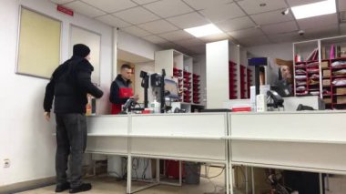 even during war parcel delivery works People come to counter to receive or send package cashiers sales assistants are looking places on shelves red vests at sellers New mail Ukraine Vinnitsa 2023