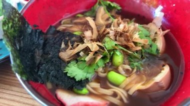 Spicy Sichuan Dandan noodles ramen with spicy dumplings combo in the traditional Japanese ramen restaurant, with Japanese fonts sake barrel translation: Invincible Great Gate. High quality photo