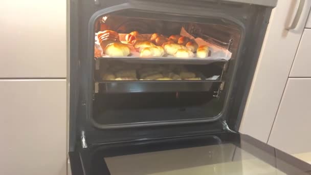 ホットドッグのパフペーストリー女性の手で焼きたての生地をオーブンから取り出す焼きたてのソーセージは ベーキングシートの上にあり 別の角度からテストで既製の自家製ソーセージ — ストック動画
