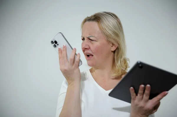 Angry woman talking on phone, looking at laptop screen, irritated woman arguing with customer client, having unpleasant conversation, holding smartphone, solving business problem woman screaming