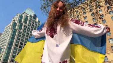 Pray for Ukraine. child with the Ukrainian flag on street. A little girl waving the national flag prays for peace. Happy kid celebrating Independence Day Teenager in downtown Vancouver against war