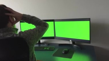 an office worker sits in front of two monitors with chromakey green screen he grabs head in horror and throws himself back in chair shows hands at monitor you ask what it is, how can it be glasses