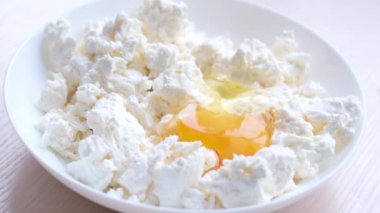 plates with cottage cheese lies 1 egg 2 egg breaks And falls spreading over filling cooking for all kinds of cheesecakes syrniki pancakes homemade breakfast Healthy food children need calcium