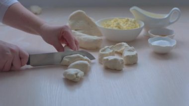 cut yeast dough Pieces of yeast dough on a board. cook sprinkles flour to prevent sticking. Front view of unrecognizable woman cutting the dough on wooden board floured. High quality FullHD footage