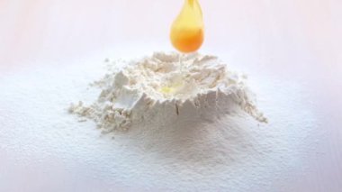 Slow motion of falling eggs into flour. Food footage. Egg dripping into flour, slow motion yolk falls into flour Food blog products Bakery products. Dough preparation flour volcano with broken egg