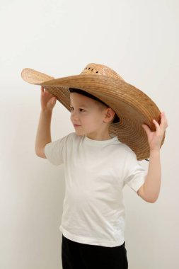 Little boy with a hat doing push-ups. Cowboy hat Cute Little Cowboy on a white background holds a hat on both sides with his hands 4-5 years old child High quality photo