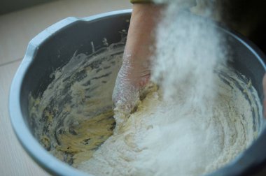 woman kneading dough by hand yeast dough liquid in process of kneading hand of elderly woman close-up squeezing flour eggs yeast and sugar in bowl in village cooking delicious food for grandchildren
