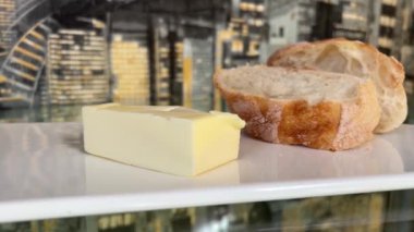 Hunk of French artisanal bread and butter white board glass table black wallpaper High quality 4k footage