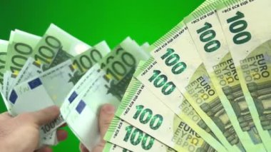 euro close-up on green background chroma key new banknotes are counted old banknotes exchange of old currency for new one lot of money wealth travel win counting money fan out banknotes of 100 euros