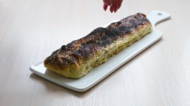 white porcelain board female hands put apple strudel sprinkled with poppy seeds cut with huge knife and turn cadru stuffing delicious cake crumble and fall around delicious dessert homemade cakes