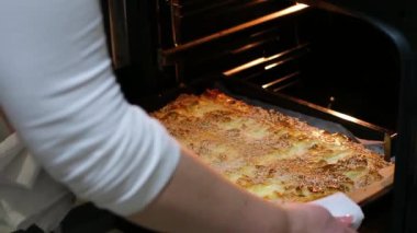 woman in white clothes with white towel missing freshly baked big pie from oven sprinkled with sesame seeds fresh pastries delicious dessert cottage cheese casserole cottage cheese pie black oven 