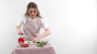 Smiling young woman serving fresh salad on plate. Happy smiling cute woman cooking fresh healthy vegan salad at home with many vegetables in kitchen and trying new recipe High quality photo