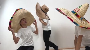 3 brothers in huge cowboy hats fooling around they hafun in middle is little boy 5 years huddled on both sides of hat as if Funtik and looks into eyes of brothers funny funny picture family vacation
