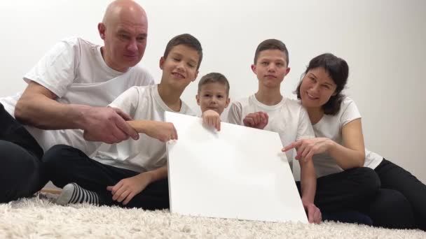 Iloinen Perhe Suuri Perhe Istuu Lattialla Niiden Edessä Valkoinen Neliö — kuvapankkivideo