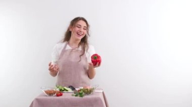 slow motion full HD 240fps young girl woman tossing red bell pepper laughing sincerely on white background space and place for text cooking show cooking appetite delicious vegetable salad vegetarian
