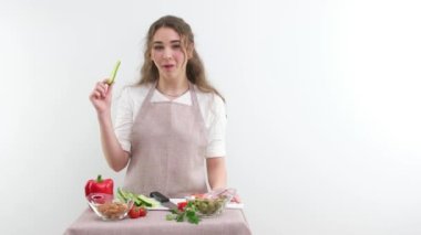 young beautiful girl cook woman nibbles fresh cucumber she shows thumb up class likes healthy food she shows index finger up choose this food there is space for text healthy food vegetable shop ad
