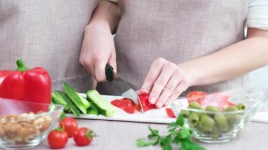 Close up cropped image of cutting board and couple cutting vegetables in the kitchen together, preparing food meal at home. Vegetarian healthy food Couple preparing a meal cut bell pepper