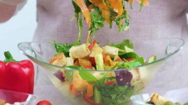 A woman mixes ingredients of vegetable salad in bowl. Close-up Mix ingredients of vegetarian salad Preparation of vegetable salad. slow motion video falling lettuce being mixed in glass plate carrots