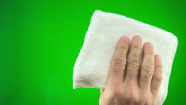 小さな布で白いタオルで画面を拭く緑の背景の男は 最終的には必要とされていないものを拭くために広告テキストのための場所がある彼の手毛深い手の指を削除します — ストック動画