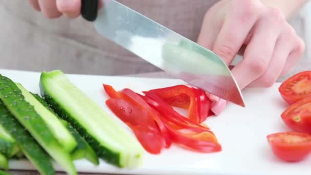 野菜の新鮮なベジタリアンサラダキュウリトマトダイエット健康的な食品の重量損失料理おいしい野菜の隣に大きなナイフの女性の手で唐辛子をカットクローズアップ — ストック動画