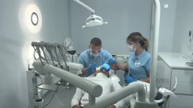 doctor in blue gloves applies an ointment to patients teeth that shows cleaning and polishing at clinic Ukraine Vinnitsa dentistry Space 2023