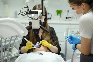 Modern dental equipment Medium shot of female dentist mask gloves using dental microscope to examine patients teeth doctor patient assistant dental treatment prosthetics canals fillings false teeth