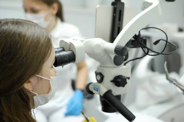 Modern dental equipment Medium shot of female dentist mask gloves using dental microscope to examine patients teeth doctor patient assistant dental treatment prosthetics canals fillings false teeth