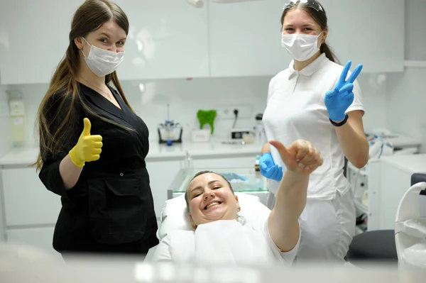 dental office satisfied patient showing thumbs up big class she liked service new technology doctor and assistant in masks are also happy with result of work smile joy dentist in black white