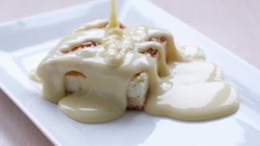 on white square plate delicious dessert is poured with condensed milk in thin stream slow motion delicious cream dripping on a pastry cake dripping caramel on plate appetizing tasty I want more